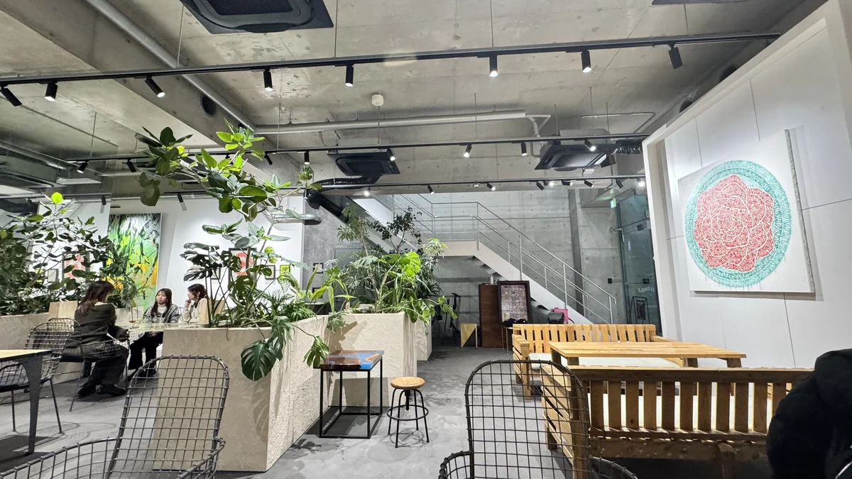 Esquisse Coffee1階の店内全景。ウッドテーブル・メッシュチェア・アート作品が並ぶ
