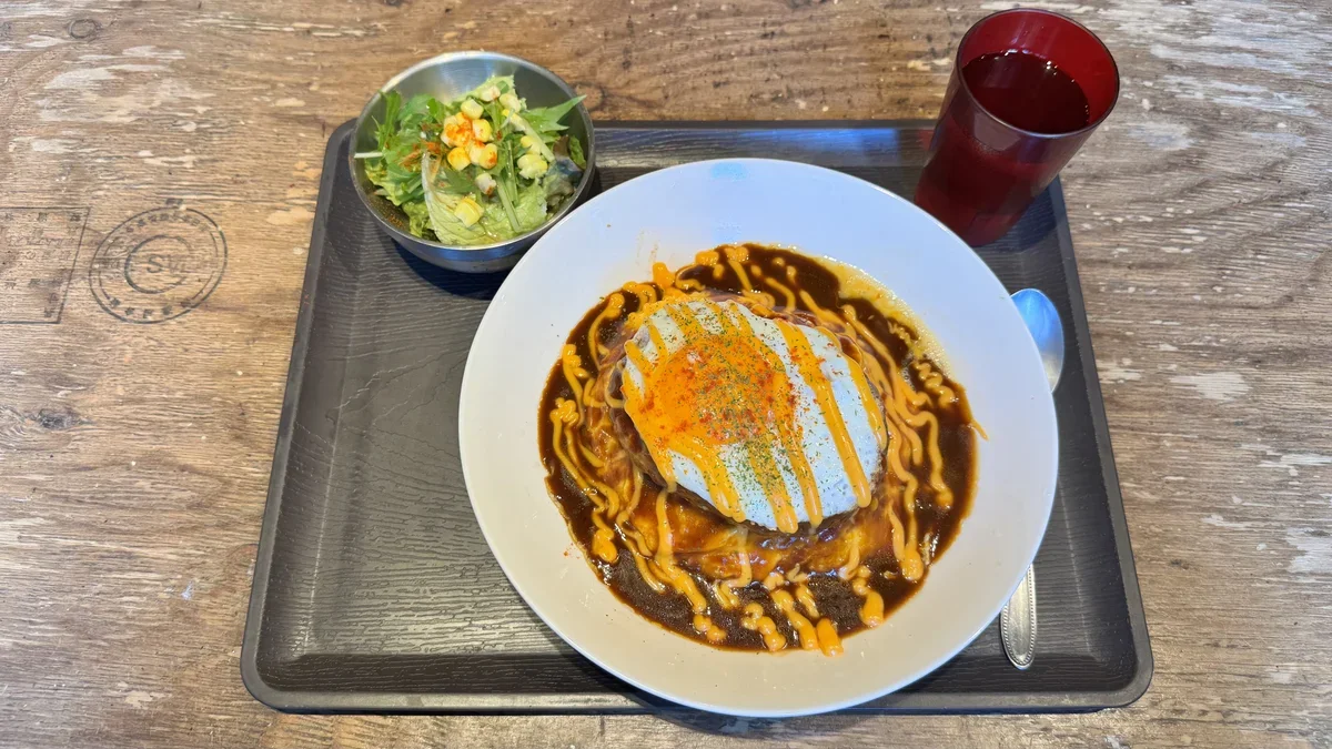チーズソースハンバーグデミライス。濃い茶色のデミグラスソースに黄色いチーズソース