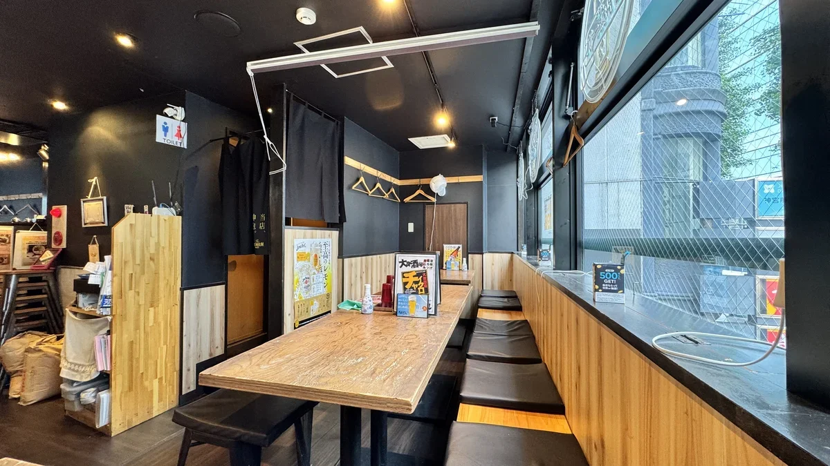 チャイクロ原宿ホール 店内。黒と木目のモダンな雰囲気。カウンター席とテーブル席がある