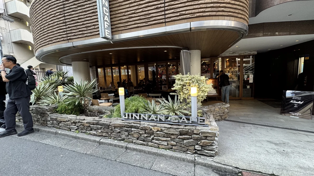 JINNAN CAFE渋谷の入口サインと植栽。石積みの花壇にアガベが並ぶ
