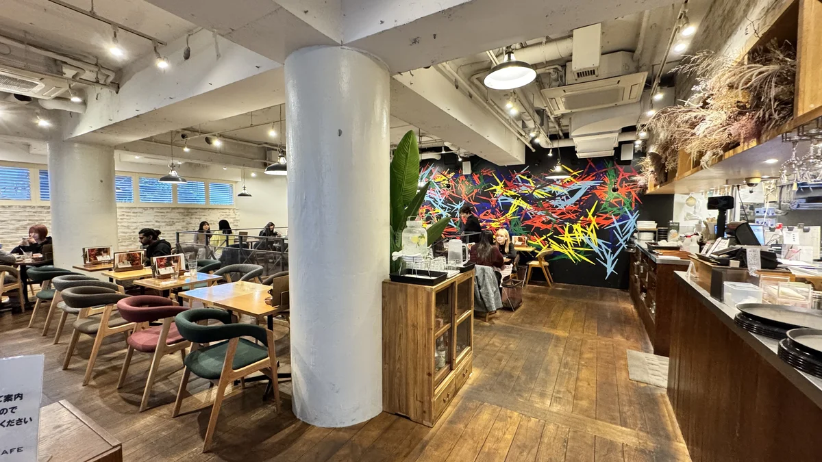 JINNAN CAFE渋谷1Fの店内全景。白レンガ壁・カラフルな壁画・多彩なチェアが並ぶ
