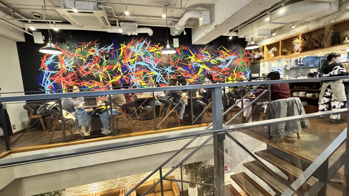 JINNAN CAFE渋谷の2Fとカラフルな抽象壁画。鉄骨の階段とともに迫力のある空間