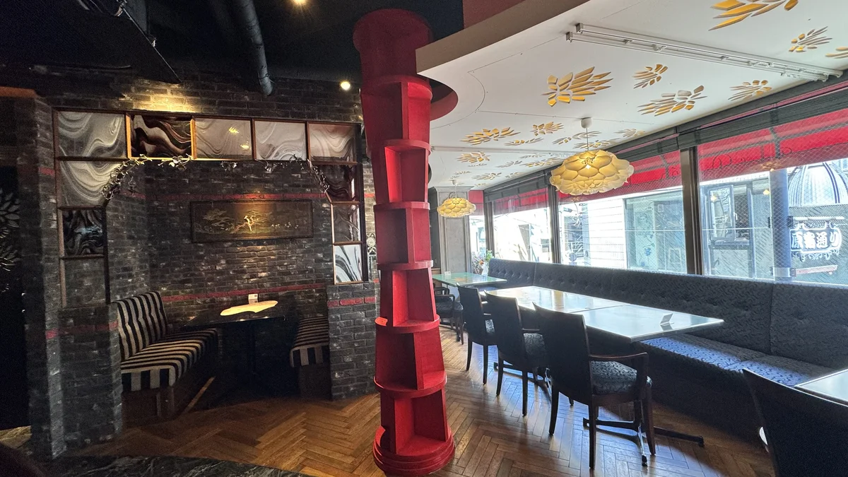 和牛鉄板焼つむぎの店内全景(赤い柱・ストライプソファ・レンガ壁・窓側テーブル席)