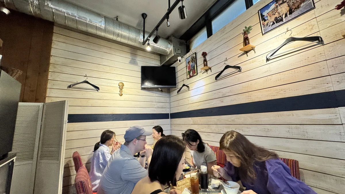 ペルー料理ALDO南青山店の店内で食事を楽しむ来店客たち。白い木板の壁とテレビ、南米風の装飾