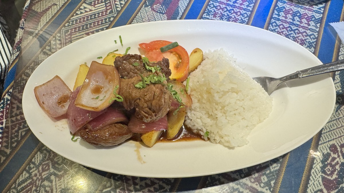 ペルー料理ALDO南青山店のロモ・サルタードを真上から撮影。牛肉と紫玉ねぎ、トマト、フライドポテト、ライスが盛られた一皿