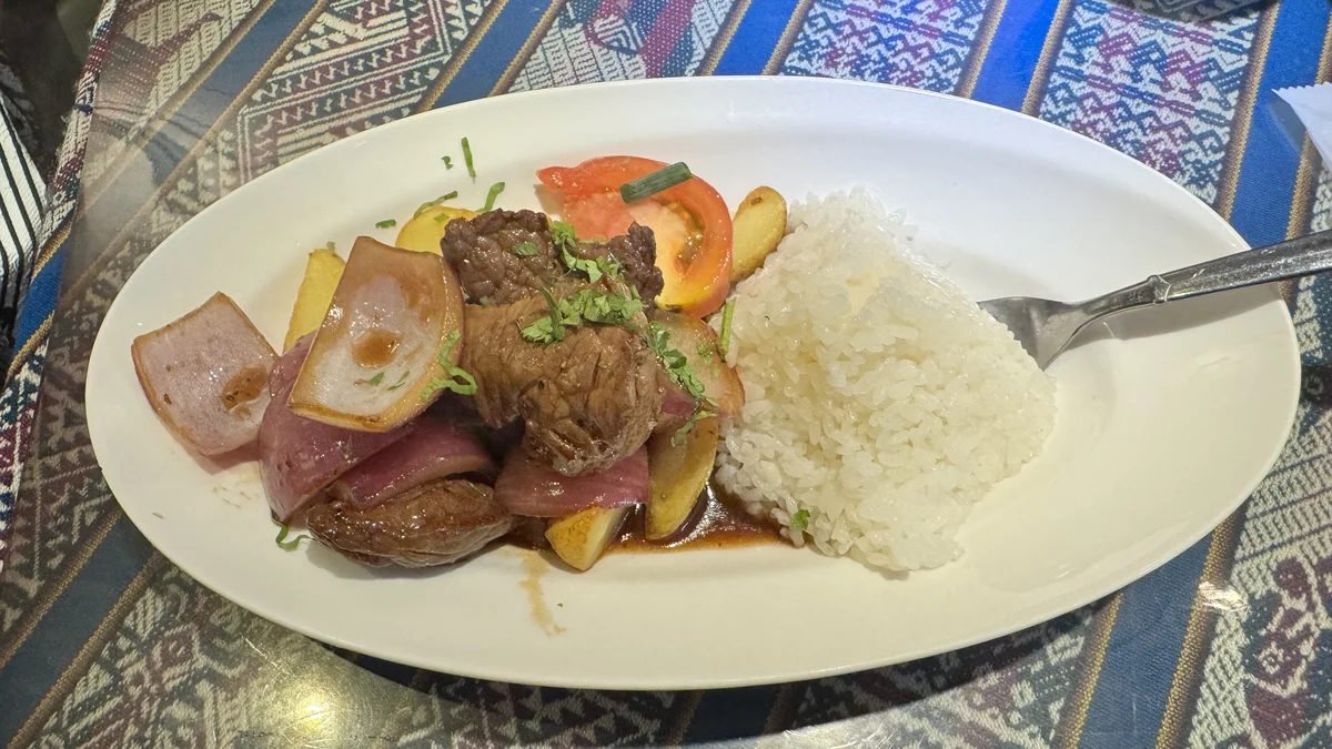 ペルー料理ALDO南青山店のロモ・サルタードを真上から撮影。牛肉と紫玉ねぎ、トマト、フライドポテト、ライスが盛られた一皿