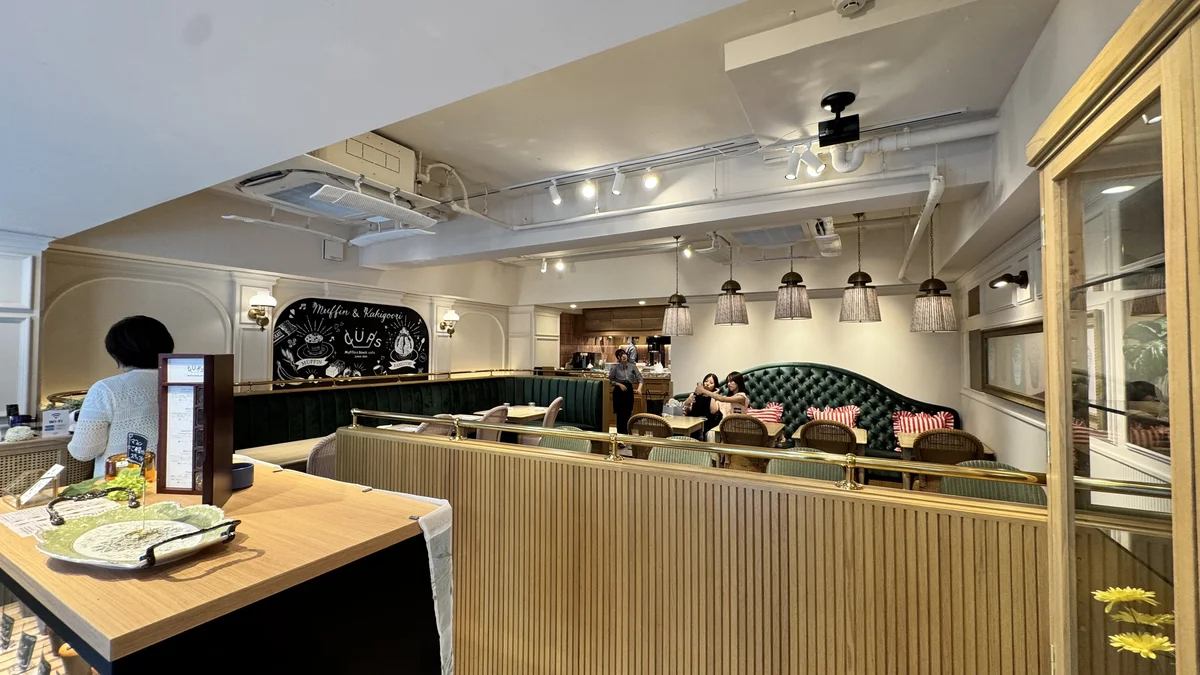 CUPS 表参道店の店内。グリーンのベロア調ソファ席と「Muffin & Kakigoori」の黒板イラスト