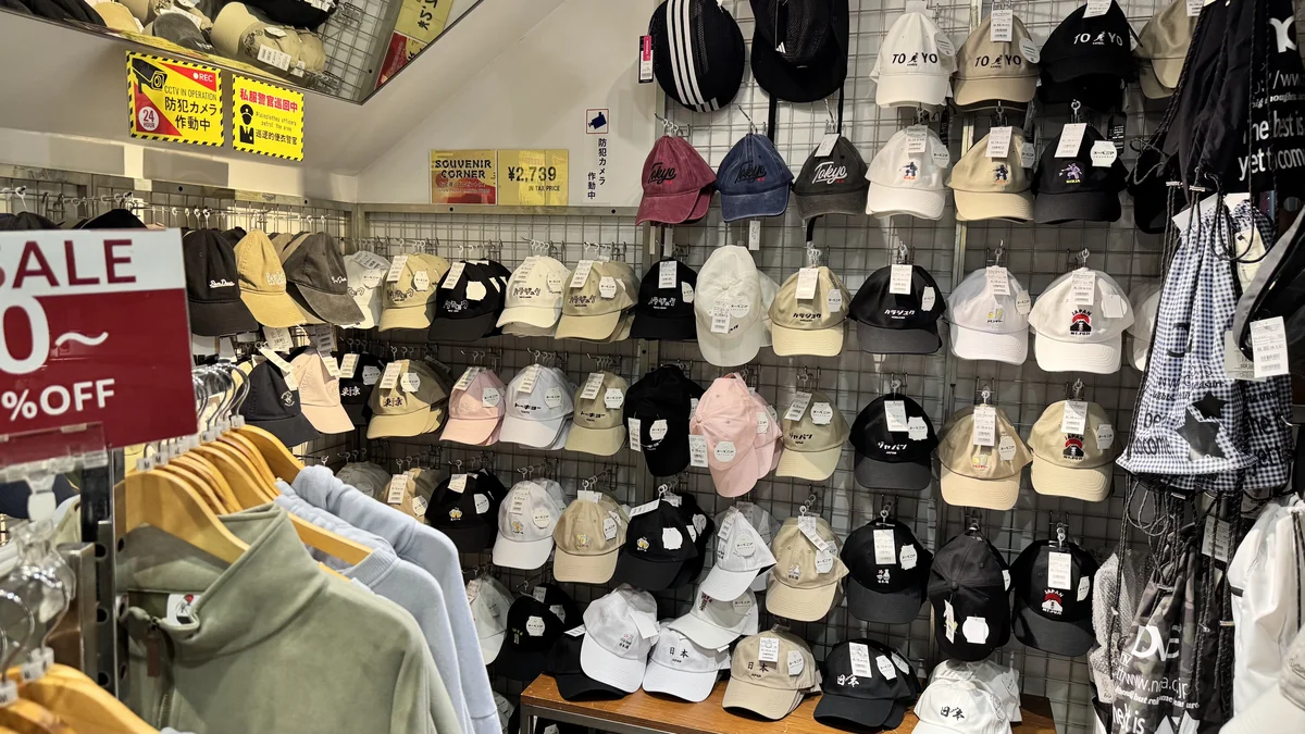 壁面に展示されたジーンズメイトのキャップ。色とりどりの帽子が数十種類並ぶ
