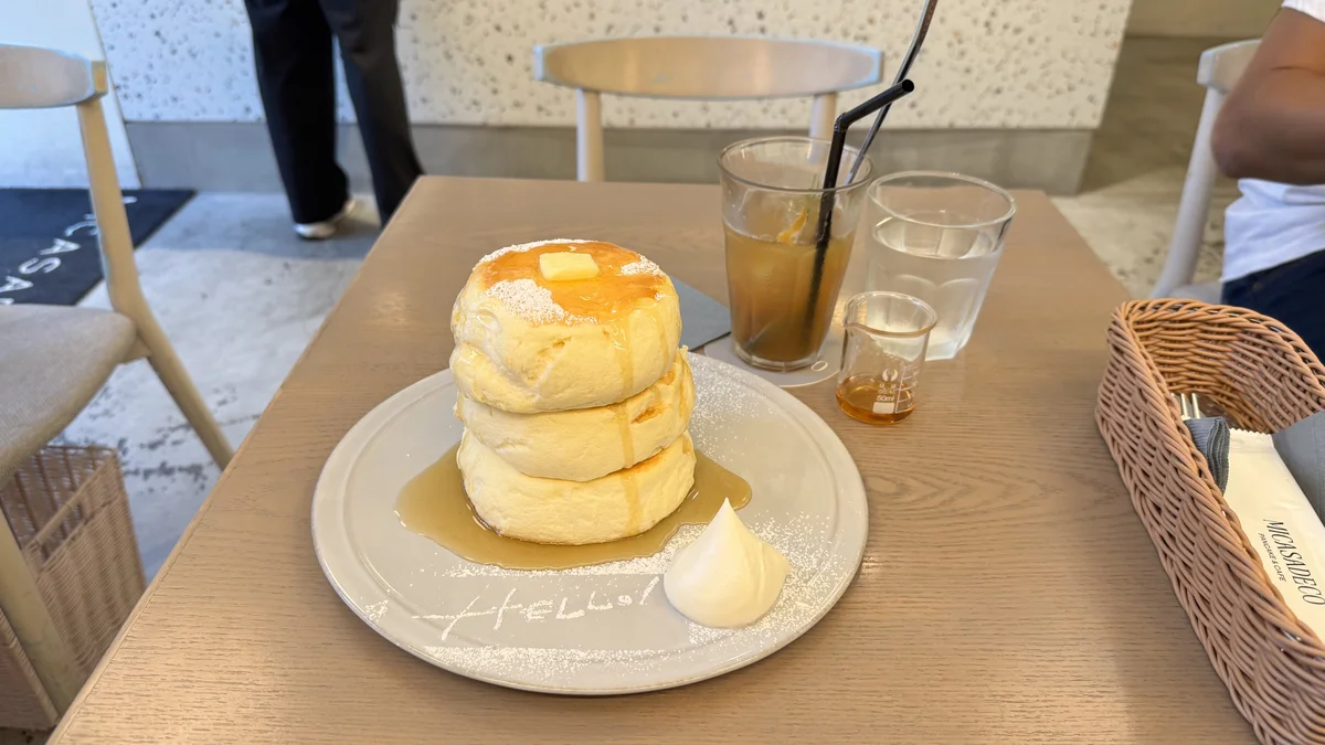 ミカサデコ&カフェの店内テーブルに置かれたリコッタチーズパンケーキとアイスティー、水のグラス