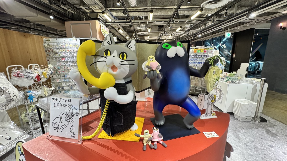 モナジアナ店内の電話猫と黒猫ムジーナの等身大フィギュア。「モナジアナ様1周年おめでとうございます」の祝いメッセージ