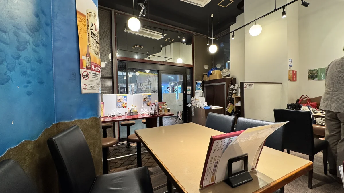 胡弓原宿店の店内。青いクラゲ柄の壁とテーブル席