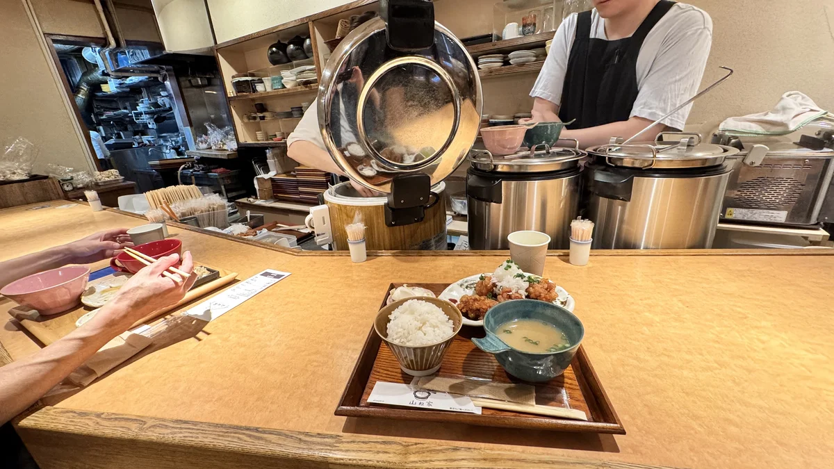 山ね家のカウンター越しに、店員がご飯をよそう様子