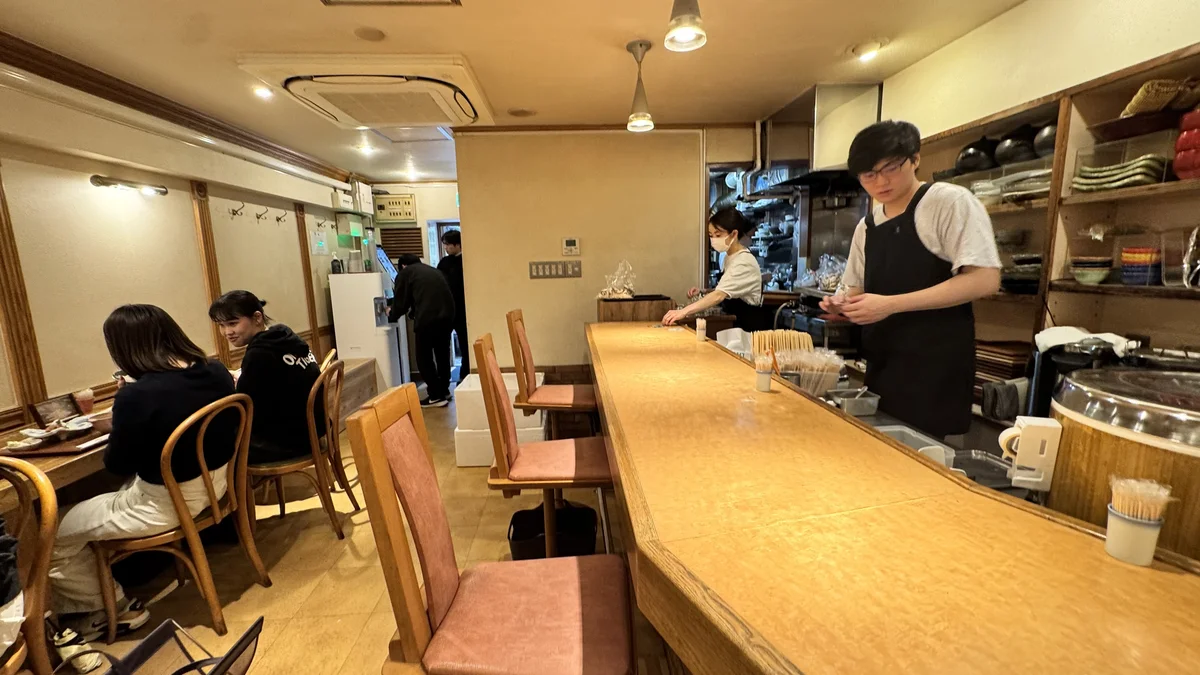 山ね家の店内。カウンター席とテーブル席があり、スタッフが厨房で作業している