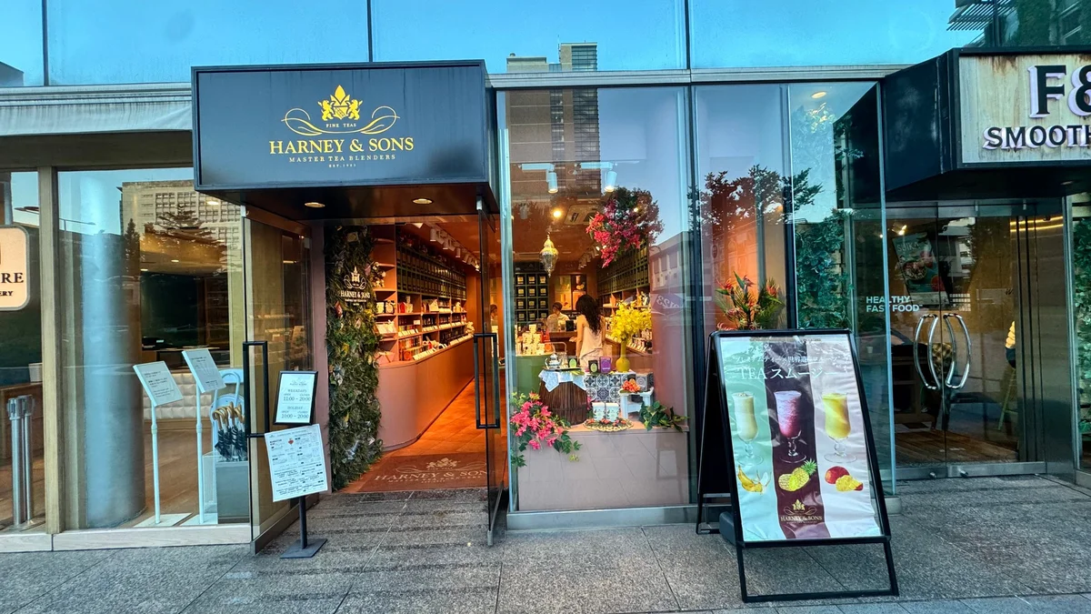 Exterior view of the HARNEY & SONS Omotesando store. The entrance on the first floor of the Aoyama Oval Building and the "TEA Smoothie" sign.