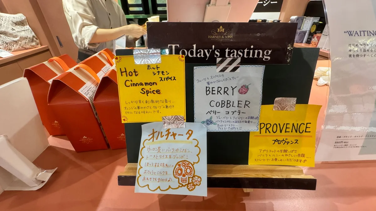The "Today's Tasting" board at the HARNEY & SONS Omotesando store. Handwritten signs for Hot Cinnamon Spice, Berry Cobbler, Provence, and Horchata.